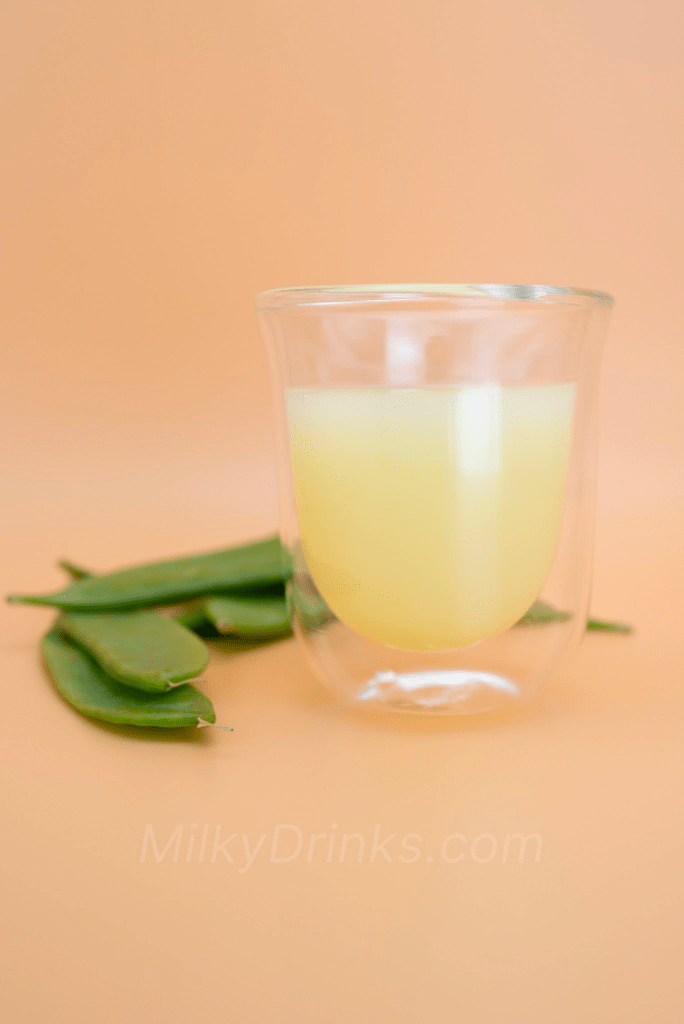Calpico Melon drink poured into a clear expresso glass with snow peas staged in the frame on a peach background