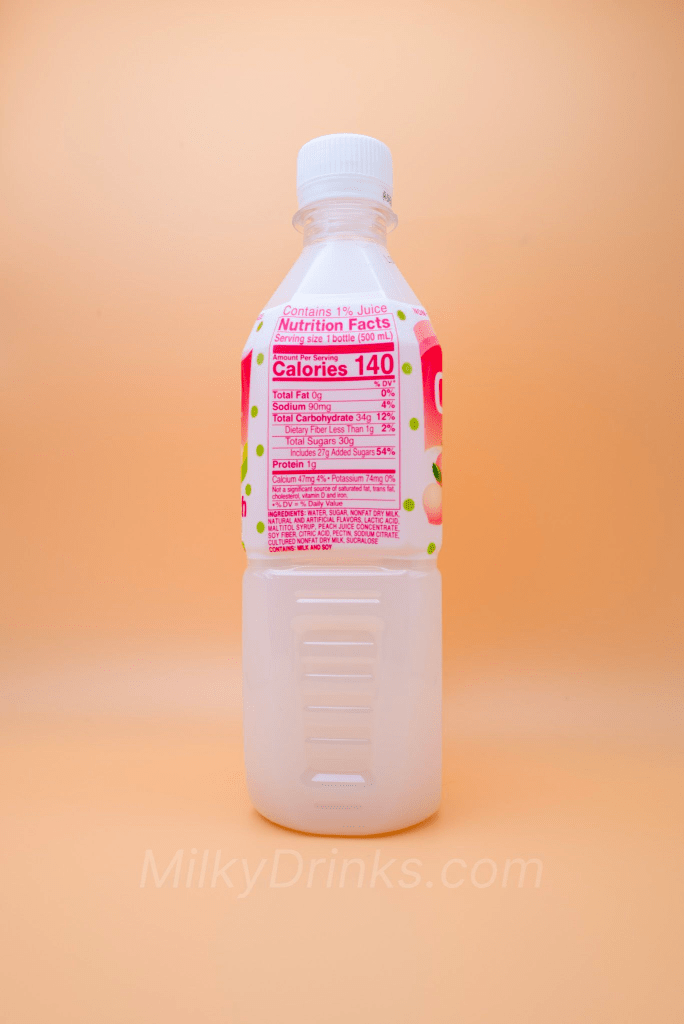 Calpico White Peach drink bottle with pink nutrition label visible, on a peach background